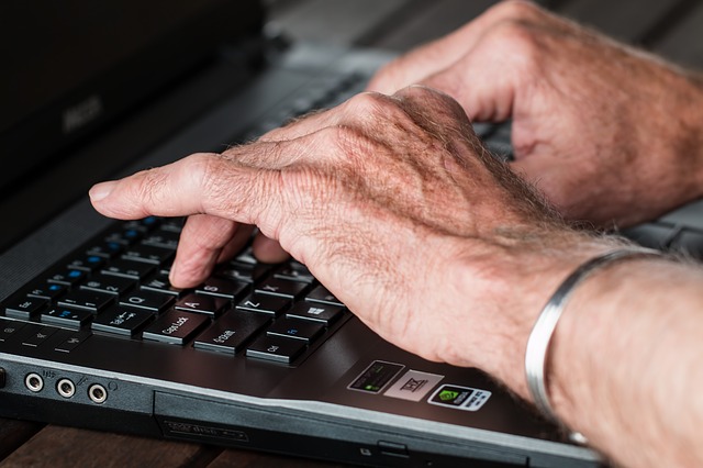 older adult typing on keyboard