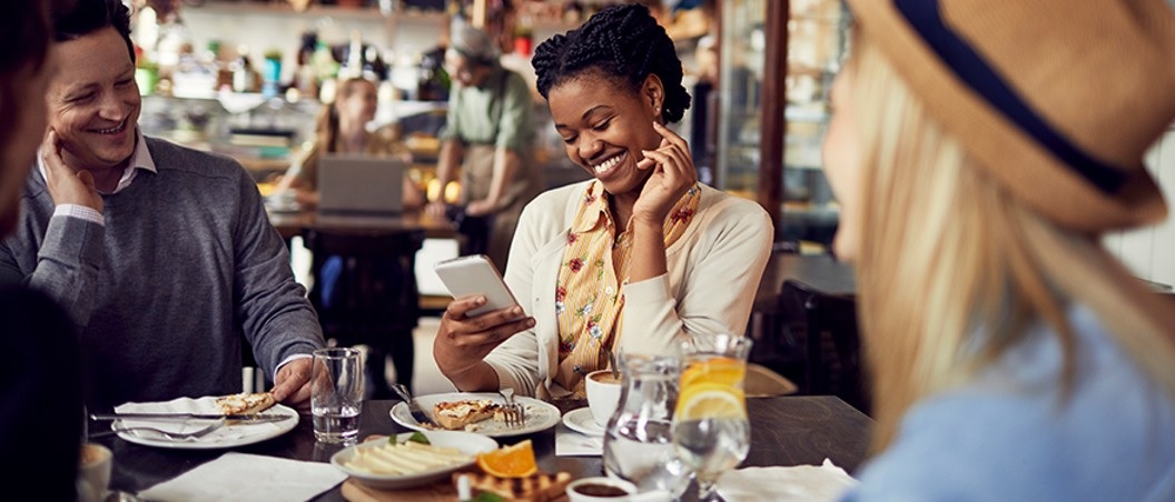ada website design near syracuse ny image of woman smiling at phone while at dinner with friends