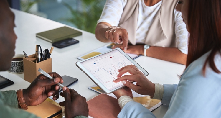 ppc marketing services employees at table looking at data on tablet