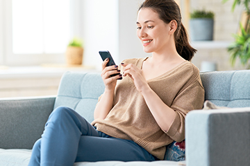 landscaping website design woman at home looking at phone while smiling