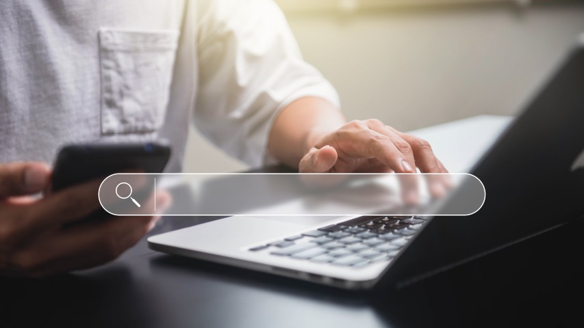 contractor website design person using phone and laptop with search bar displayed
