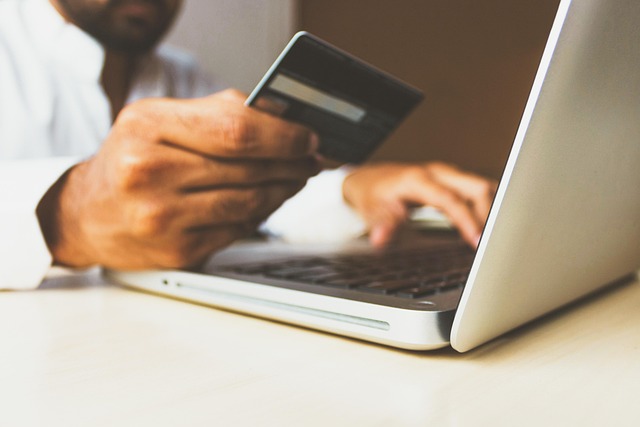 social media marketing man holding credit card while on laptop